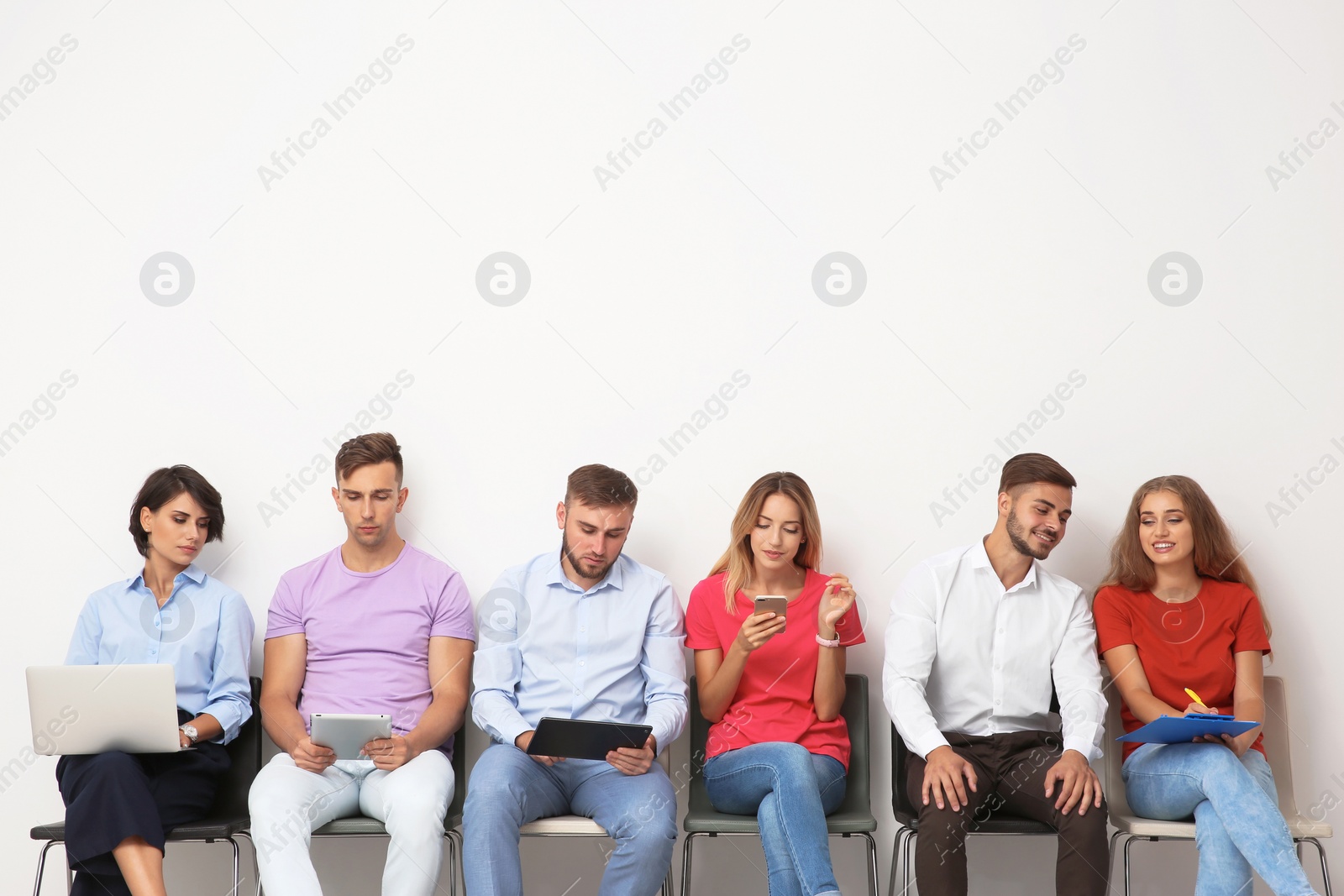 Photo of Group of young people waiting for job interview near light wall