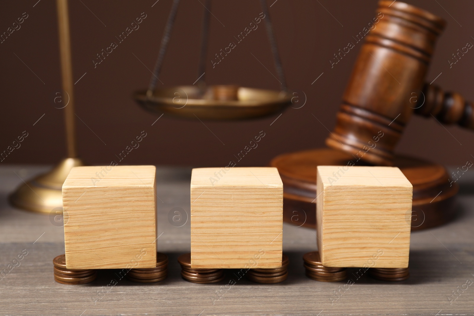 Photo of Law. Blank cubes, coins and gavel on wooden table against brown background