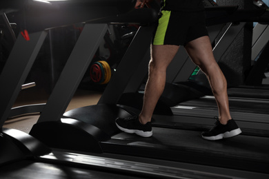 Photo of Man working out on treadmill in modern gym, closeup of legs