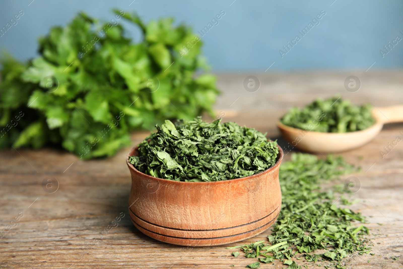 Photo of Bowl of dried parsley on wooden table