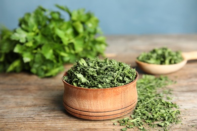 Photo of Bowl of dried parsley on wooden table