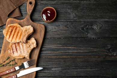 Photo of Grilled meat served with sauce on wooden background, flat lay. Space for text