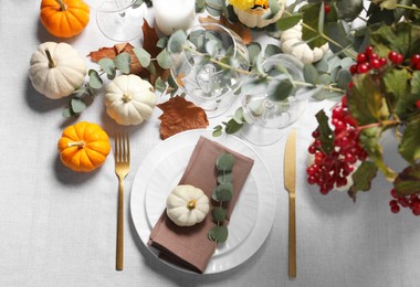 Beautiful autumn table setting. Plates, cutlery, glasses, pumpkins and floral decor, flat lay