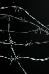 Photo of Metal barbed wire on black background, closeup