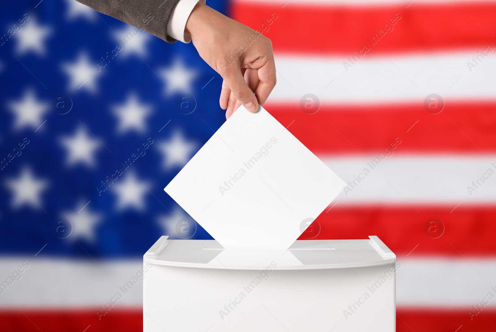 Image of Election in USA. Man putting his vote into ballot box against national flag of United States, closeup