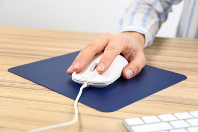 Woman using modern wired optical mouse at office table, closeup