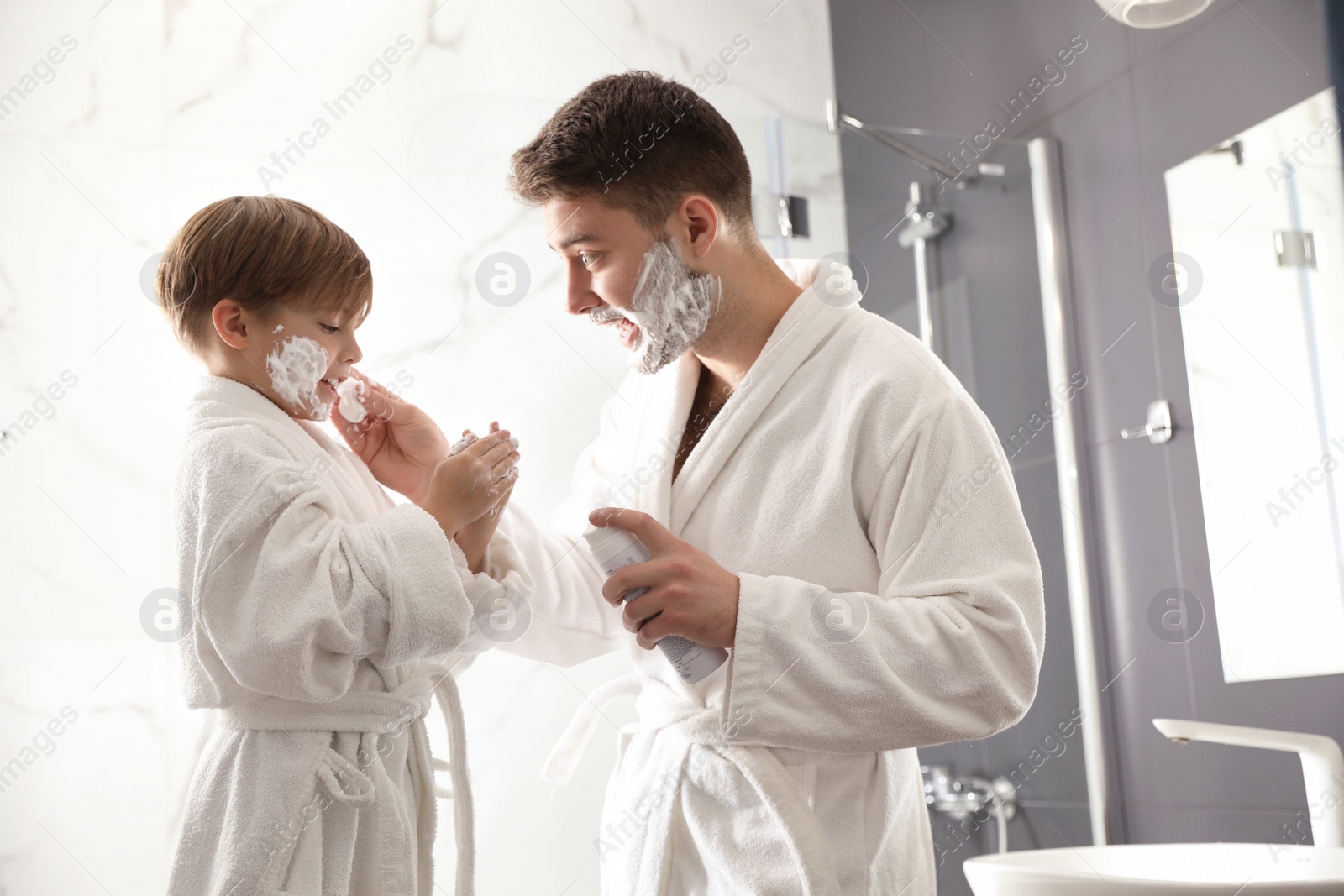 Photo of Dad applying shaving foam onto son's face in bathroom