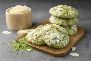 Tasty matcha cookies, almond flakes and powder on grey table