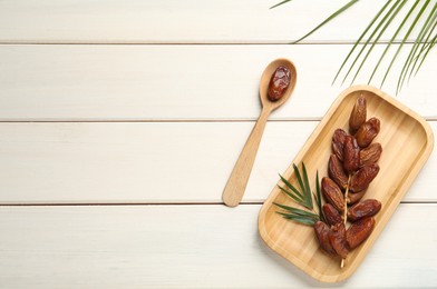 Flat lay composition with tasty sweet dried dates on white wooden table. Space for text