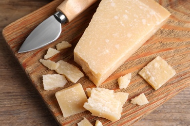 Photo of Parmesan cheese with knife on wooden table, top view