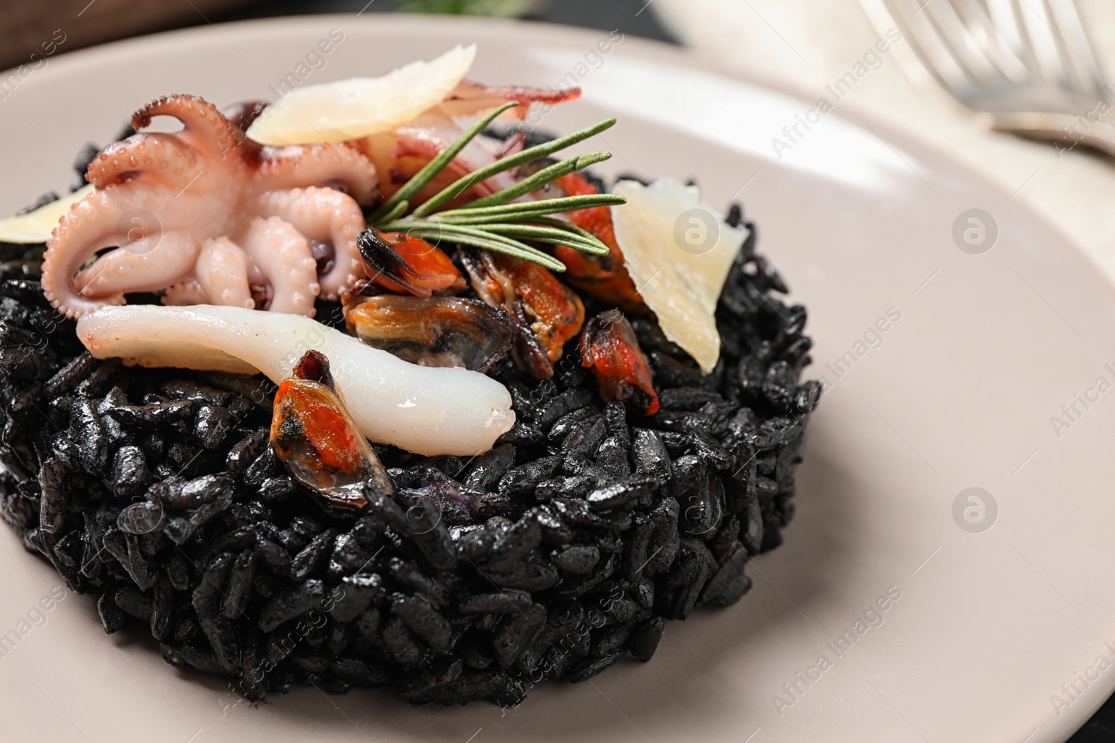 Photo of Delicious black risotto with seafood in plate, closeup