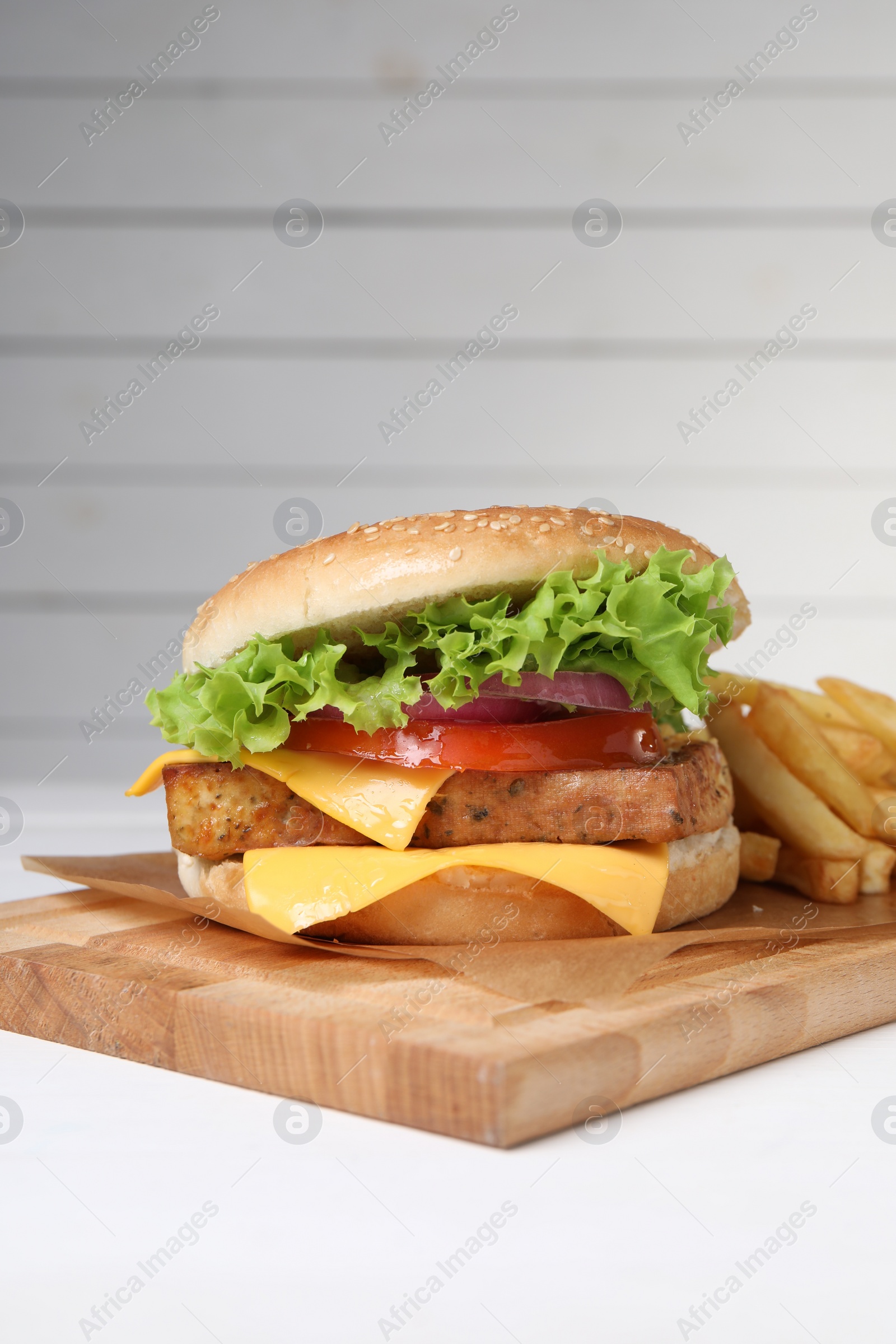 Photo of Delicious tofu burger served with french fries on white table