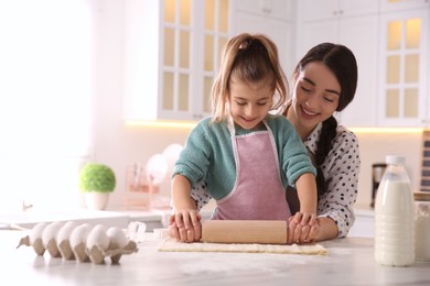 Mother and daughter rolling out dough in kitchen at home