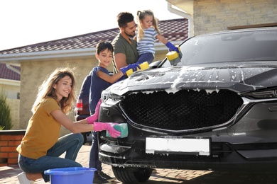 Photo of Happy family washing car at backyard on sunny day