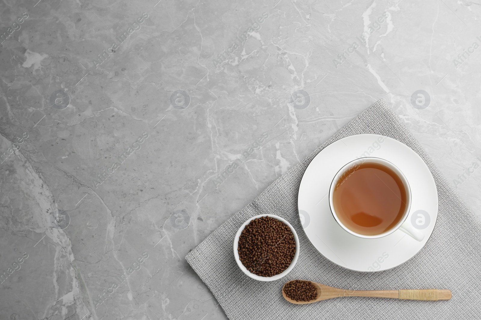 Photo of Buckwheat tea and granules on light grey marble table, flat lay. Space for text