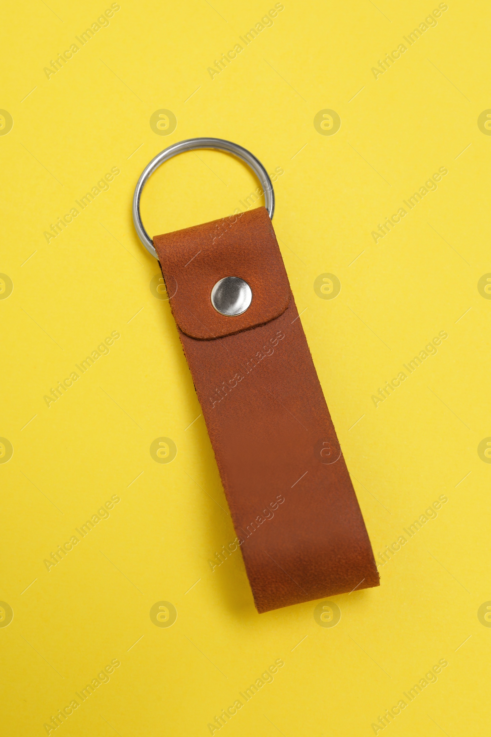 Photo of Leather keychain with Ukrainian coat of arms on yellow background, top view