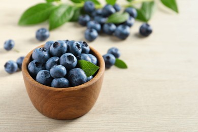 Photo of Bowl of fresh tasty blueberries on white wooden table, closeup. Space for text
