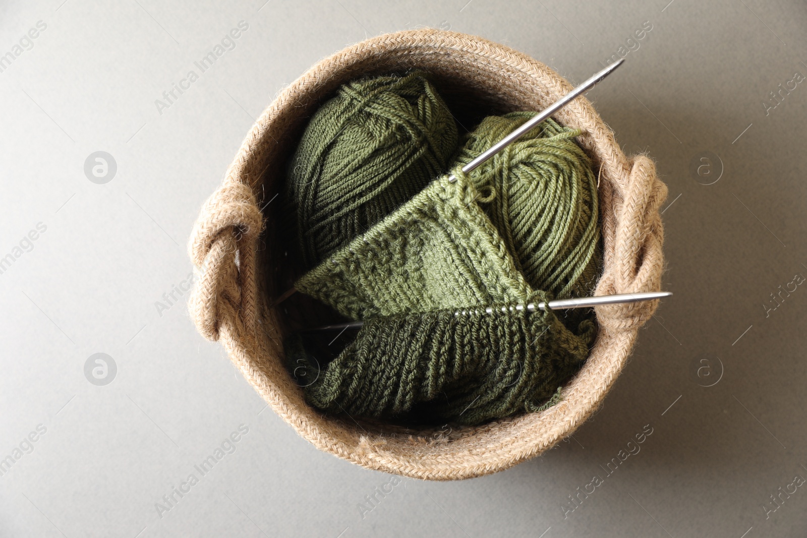 Photo of Green knitting, needles and soft yarns on light background, top view