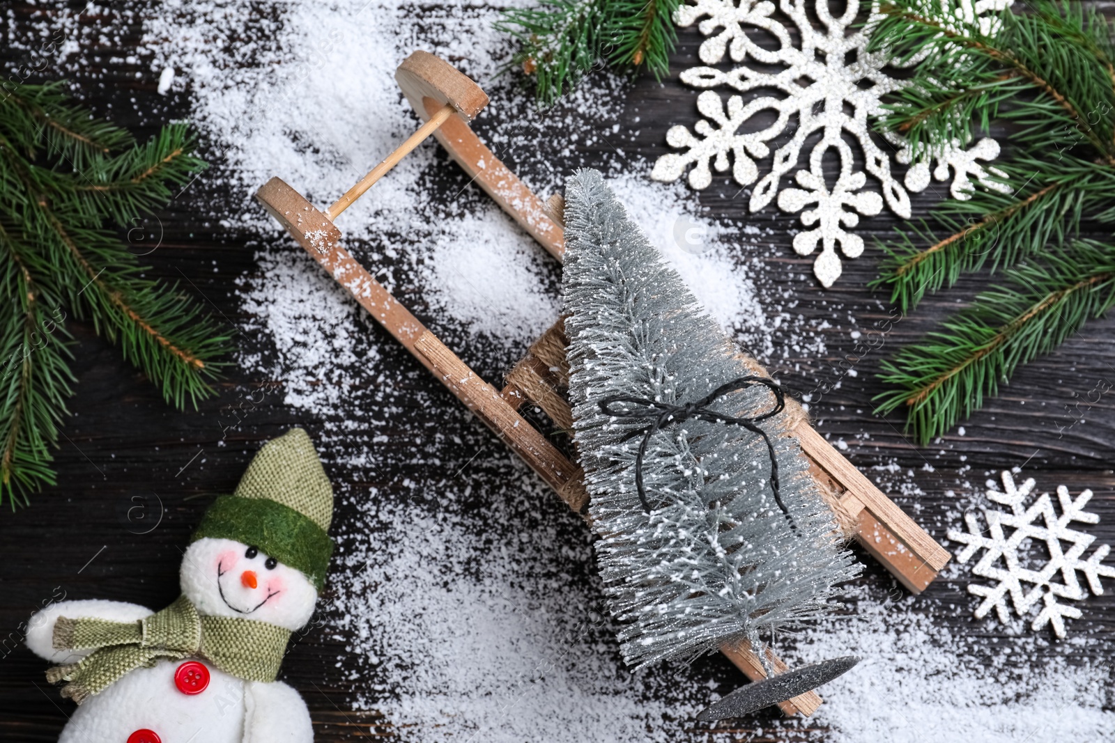 Photo of Flat lay composition with sleigh, decorative Christmas tree and toy snowman on black wooden table