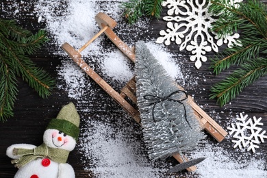 Flat lay composition with sleigh, decorative Christmas tree and toy snowman on black wooden table