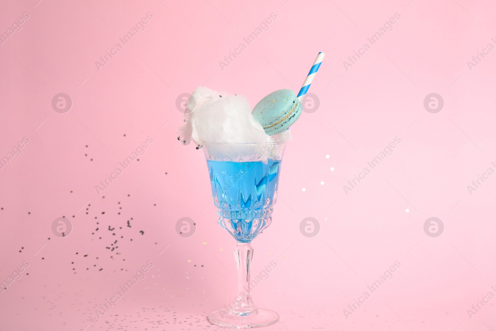 Photo of Cocktail with cotton candy in glass on pink background