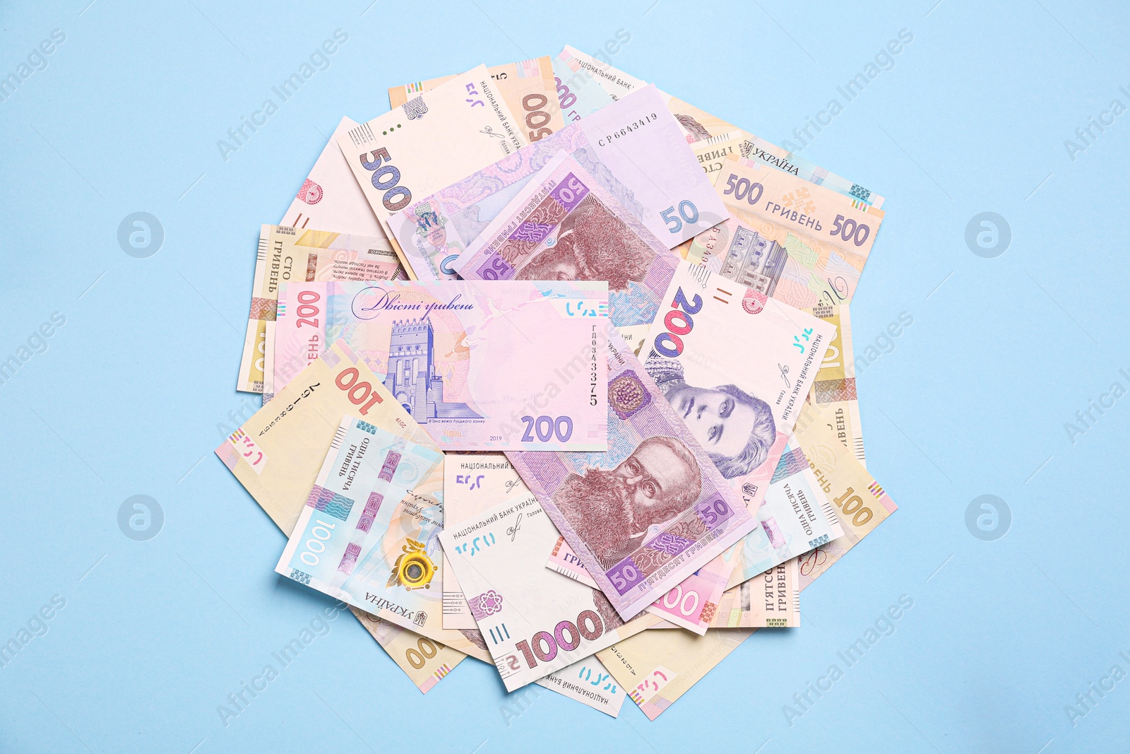 Photo of Ukrainian money on light blue background, flat lay