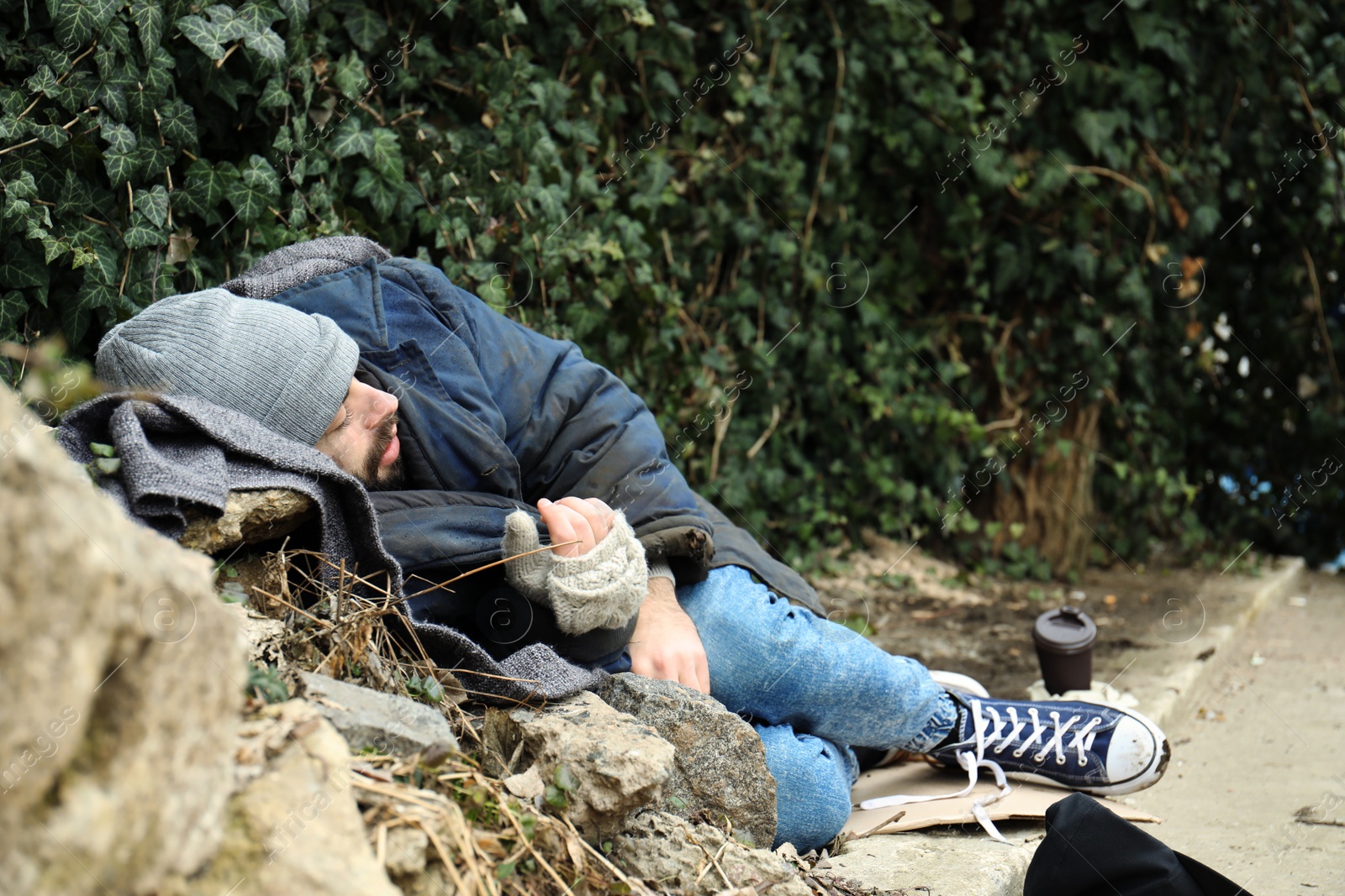 Photo of Poor homeless man lying on street in city