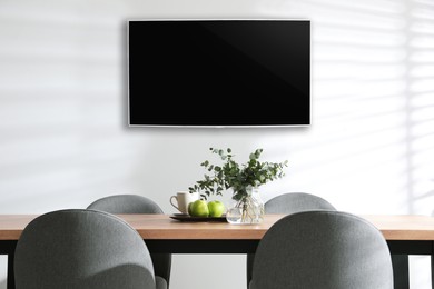 Image of Modern wide screen TV on white wall in room with stylish furniture 