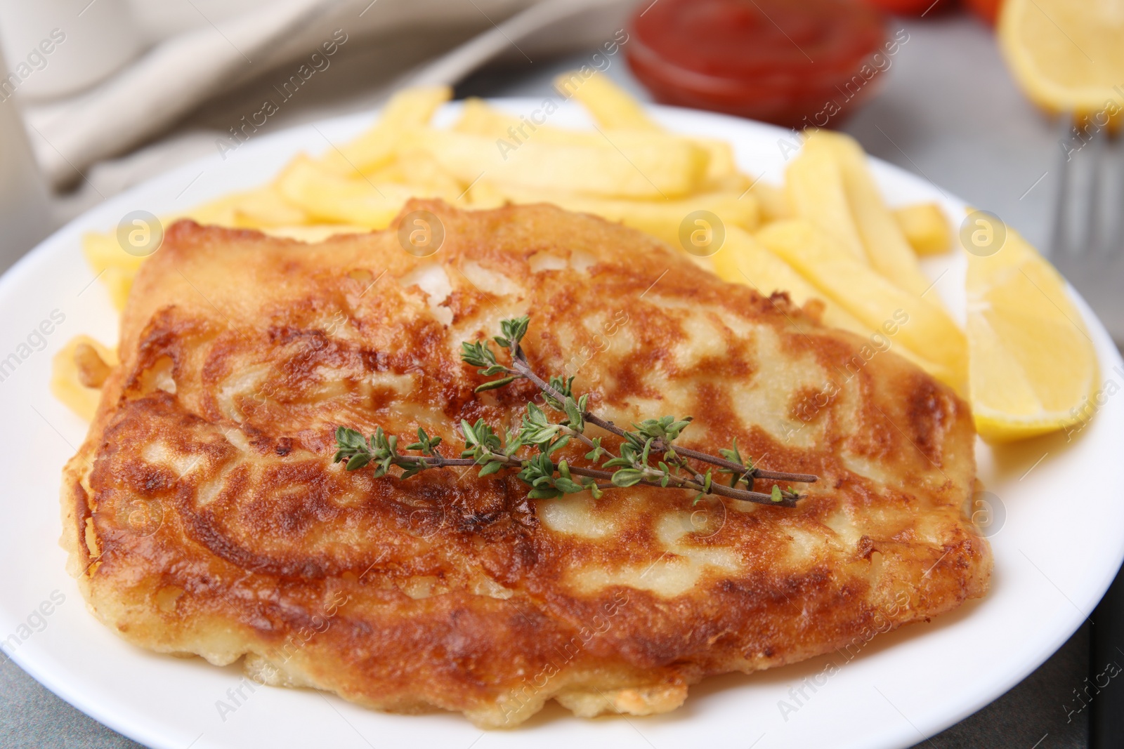 Photo of Tasty soda water battered fish, potato chips and lemon slice on plate, closeup