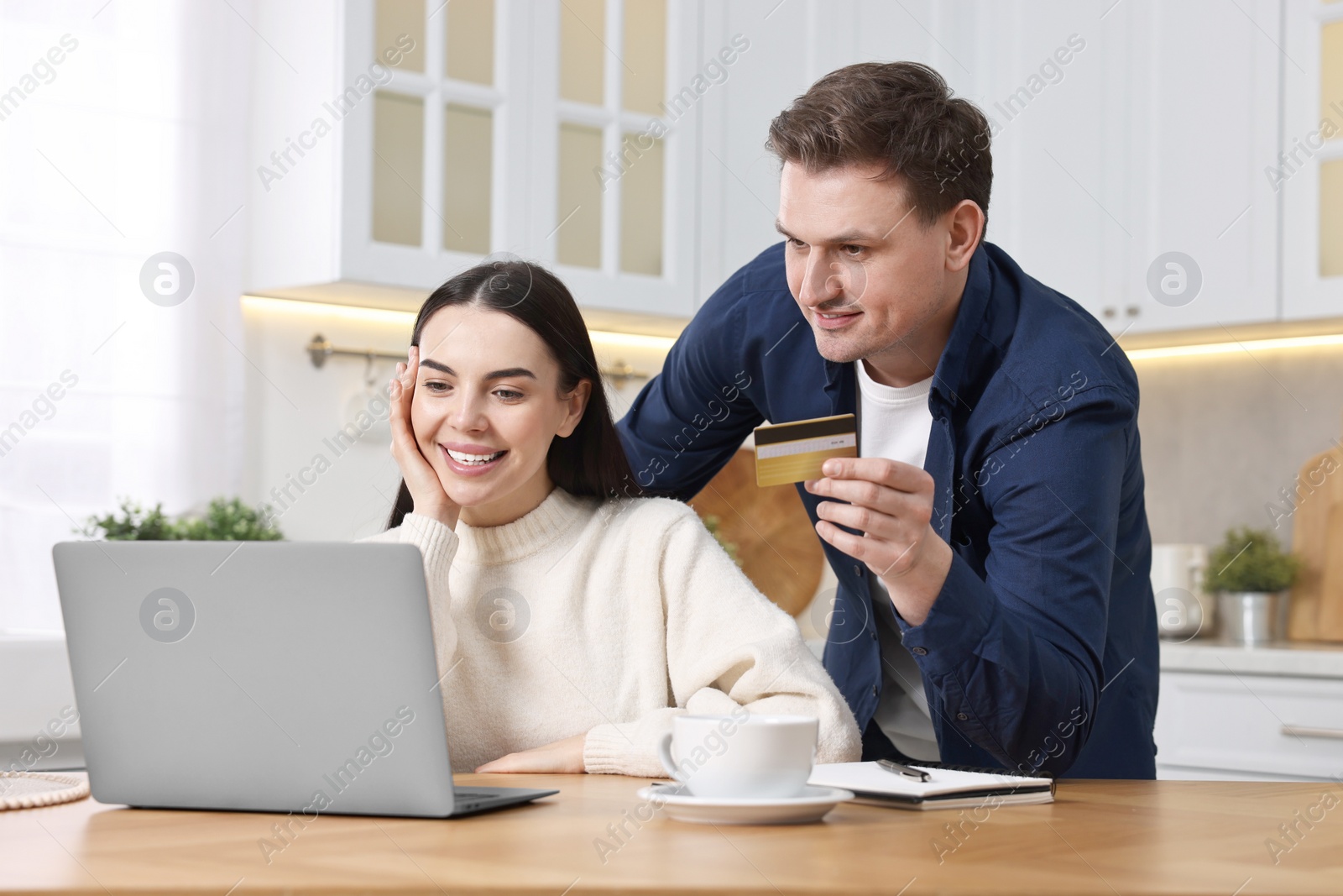 Photo of Happy couple with laptop and credit card shopping online in kitchen