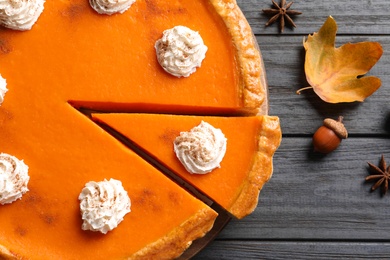 Fresh delicious homemade pumpkin pie with whipped cream on wooden background, top view