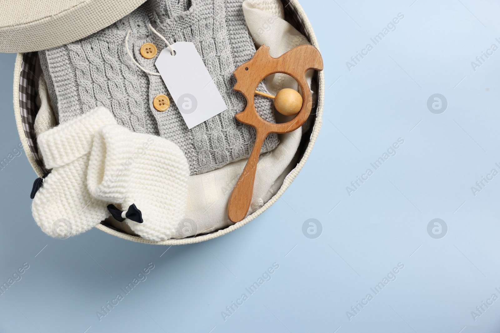 Photo of Different baby accessories and clothes in box on light blue background, top view. Space for text