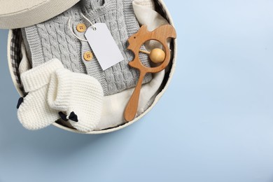 Different baby accessories and clothes in box on light blue background, top view. Space for text