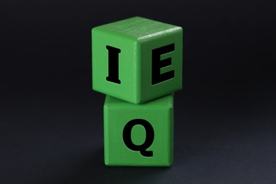 Photo of Green cubes with letters E, I and Q on black background