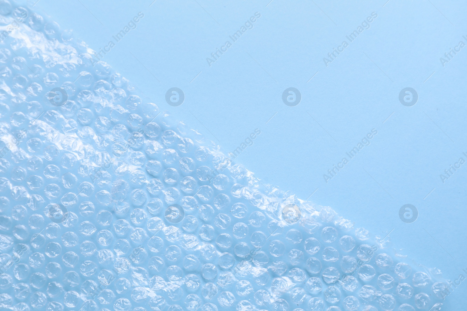 Photo of Transparent bubble wrap on light blue background, top view. Space for text