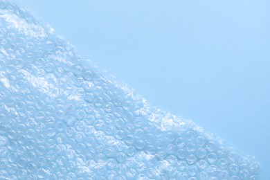 Photo of Transparent bubble wrap on light blue background, top view. Space for text