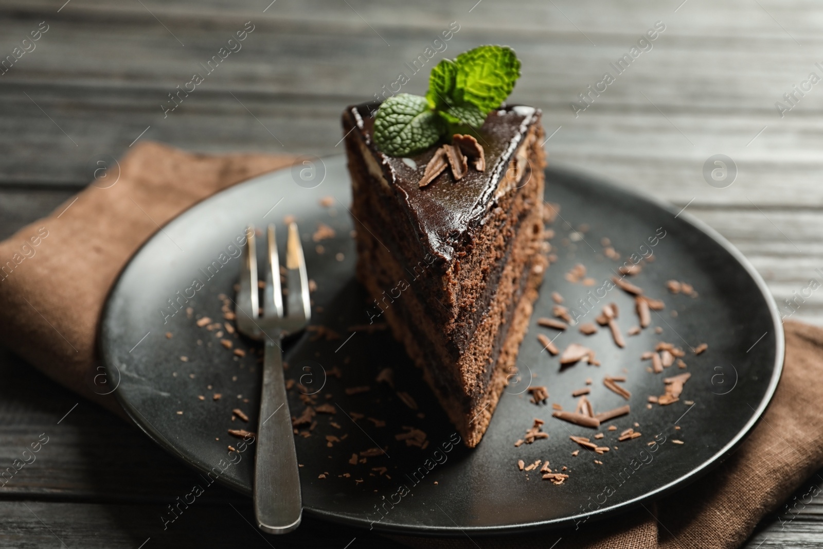 Photo of Plate with slice of chocolate cake and fork on wooden table