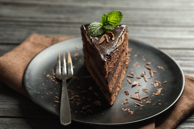 Photo of Plate with slice of chocolate cake and fork on wooden table