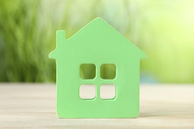 Photo of Mortgage concept. House model on white wooden table against blurred green background