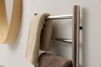 Photo of Heated towel rail with towels in bathroom, closeup