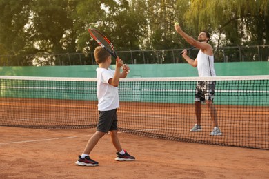 Photo of Father with his son playing tennis on court