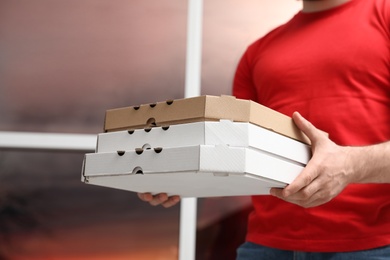 Photo of Courier with pizza boxes on blurred background, closeup