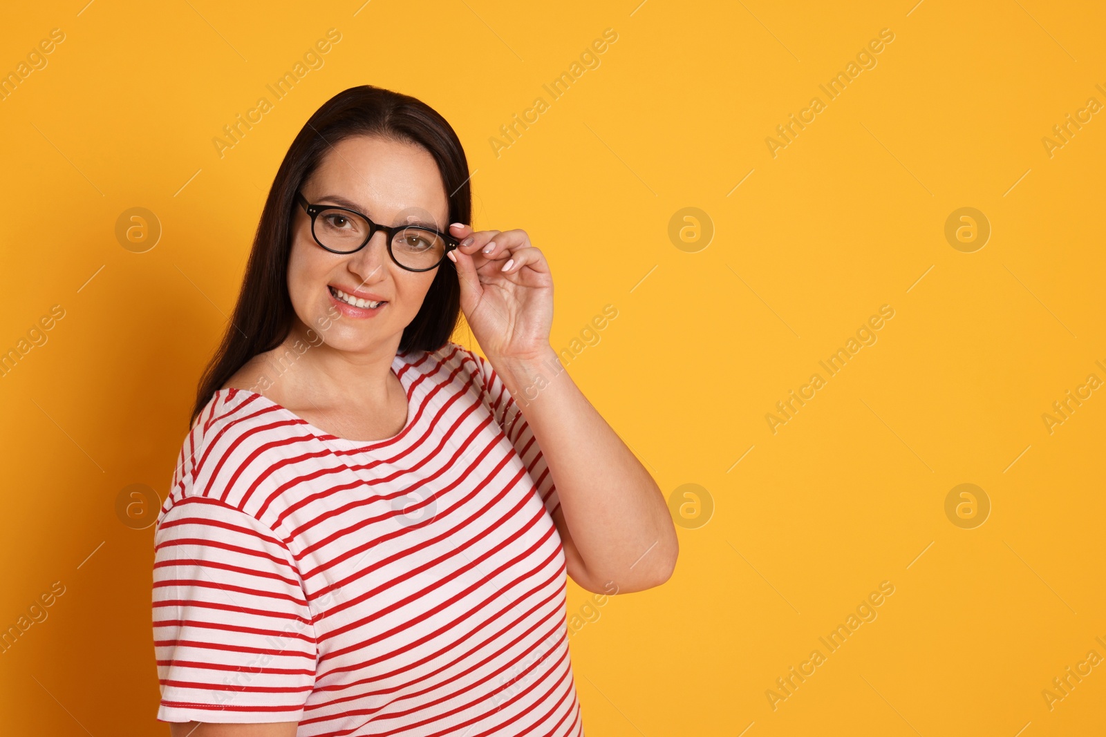 Photo of Beautiful overweight woman in eyeglasses on yellow background. Space for text