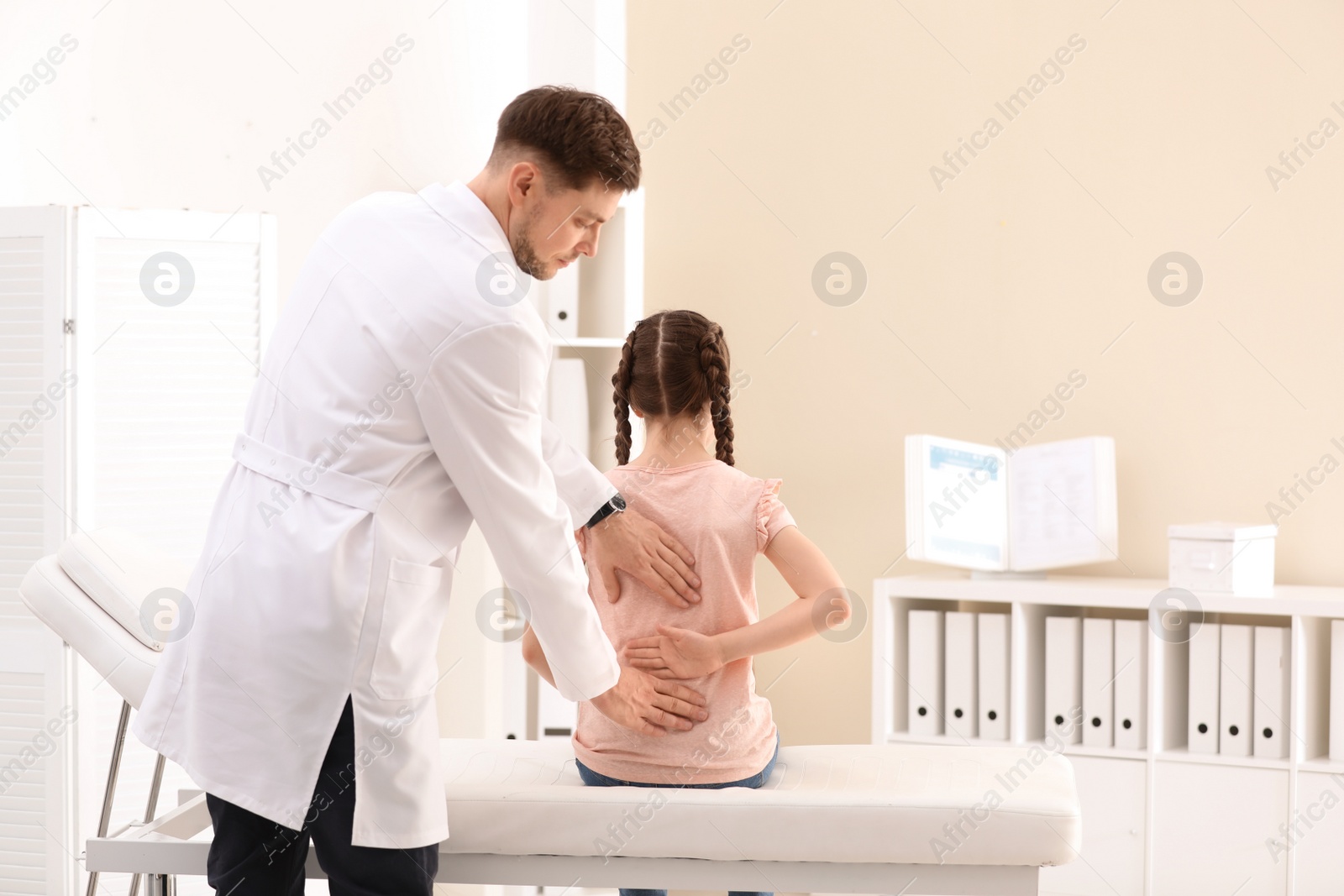 Photo of Chiropractor examining child with back pain in clinic