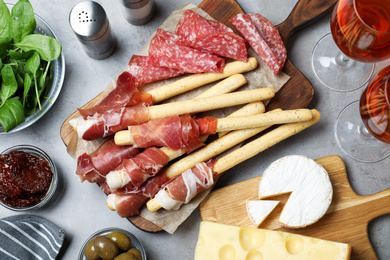 Tasty prosciutto served on light grey table, flat lay