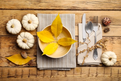 Photo of Seasonal table setting with pumpkins and other autumn decor on wooden background, flat lay