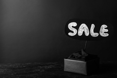 Photo of Package and card with word Sale on dark background, space for text. Black Friday concept