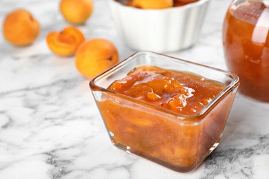 Photo of Bowl with tasty apricot jam on table