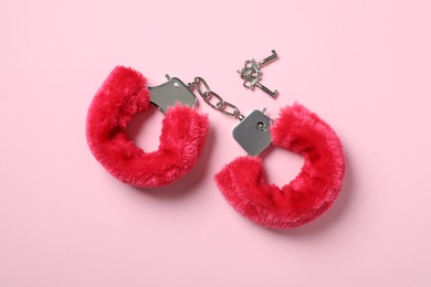 Photo of Red furry handcuffs and keys on pink background, top view. Sex toy