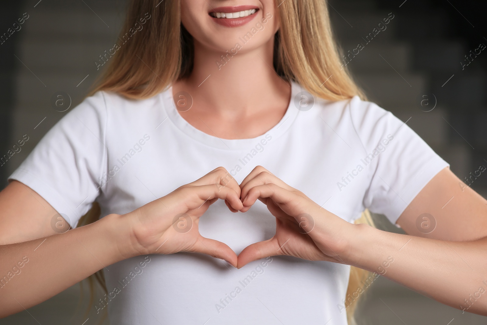 Photo of Young woman making heart with hands indoors, closeup. Volunteer concept